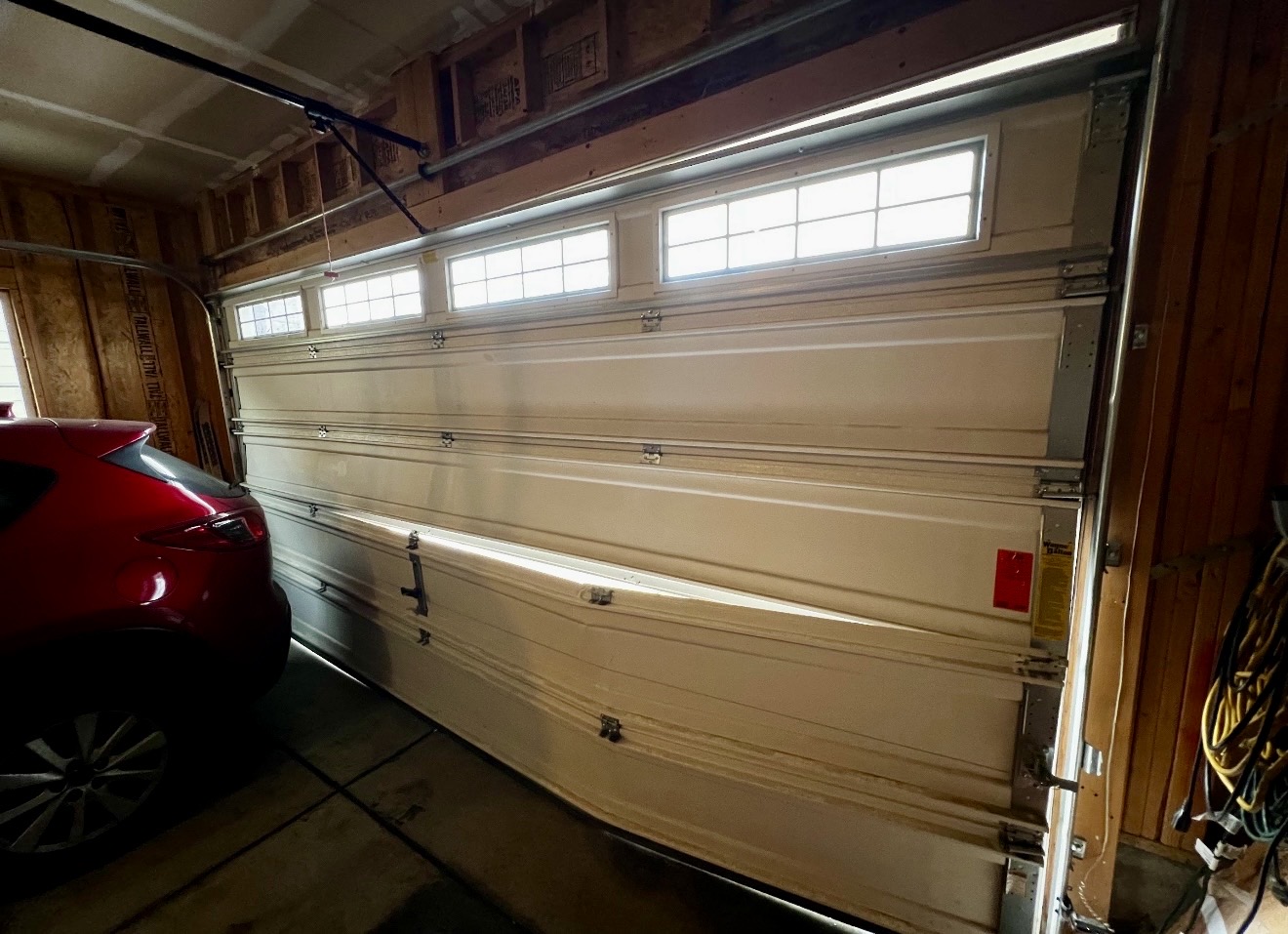 Severely buckled garage door viewed from inside