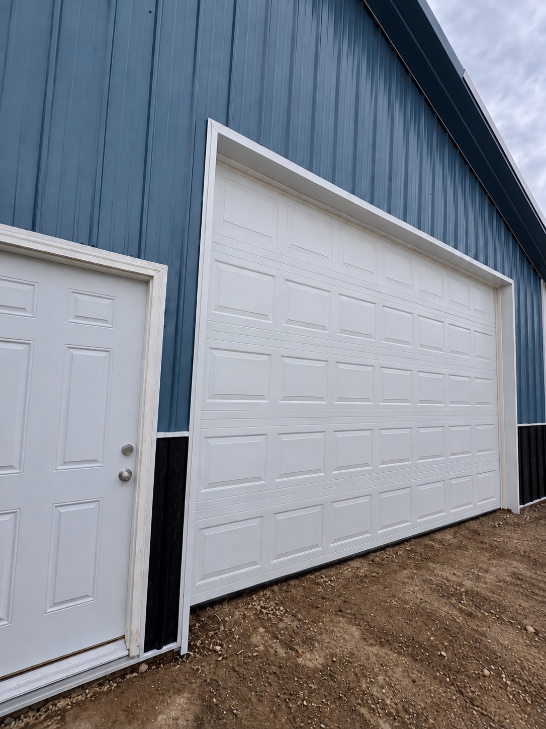 White overhead door installed on a blue pole barn